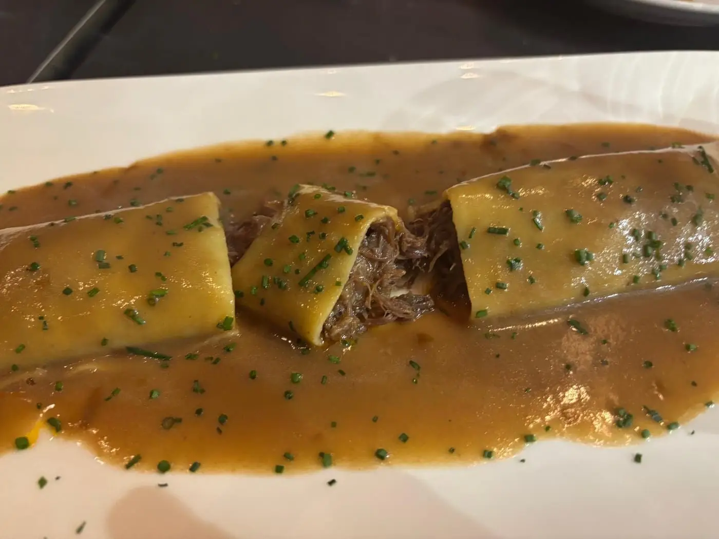 Cachopo fileteado cubierto de queso fundido con salsa y cebollino