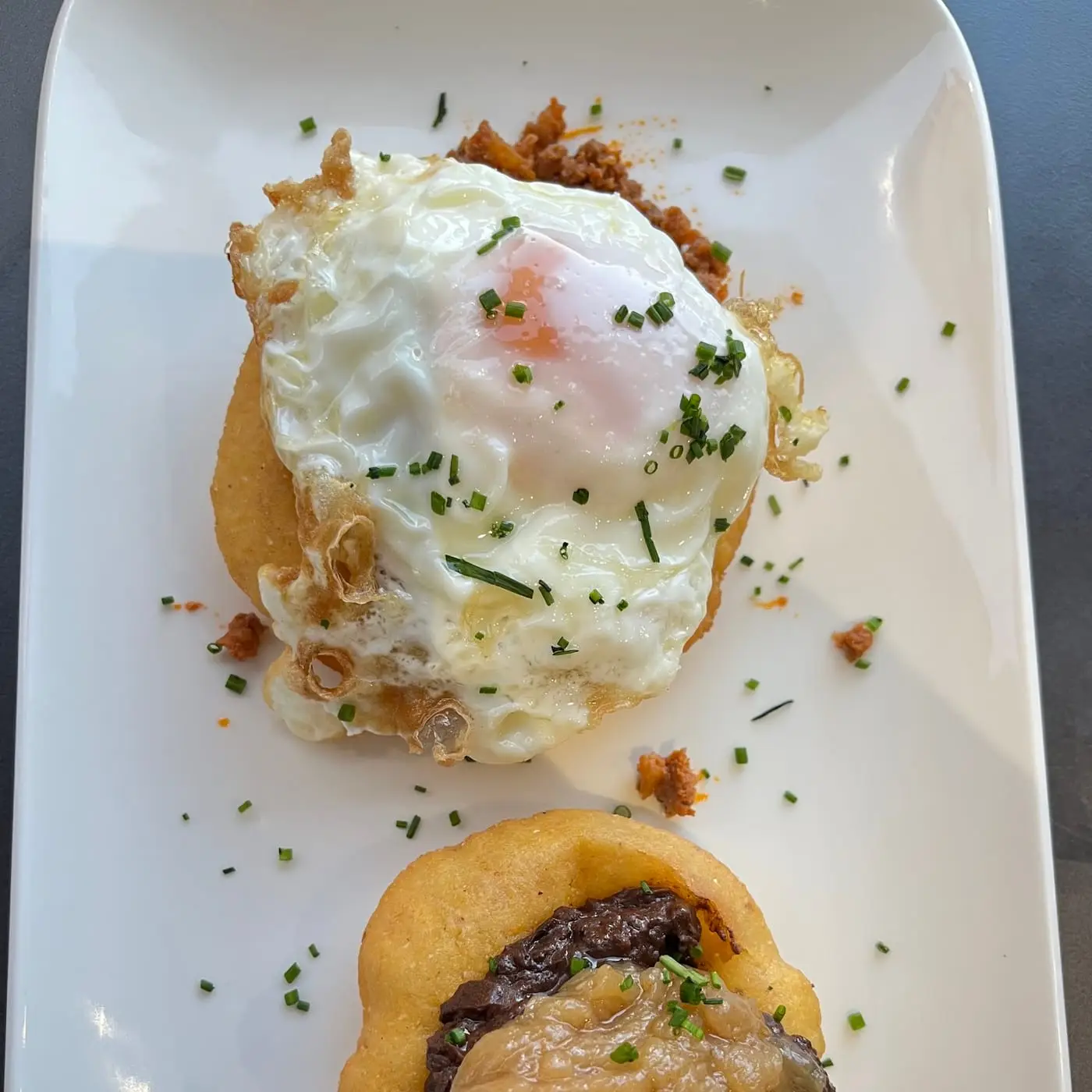 Croquetas caseras con huevo frito y jamón, espolvoreadas con perejil