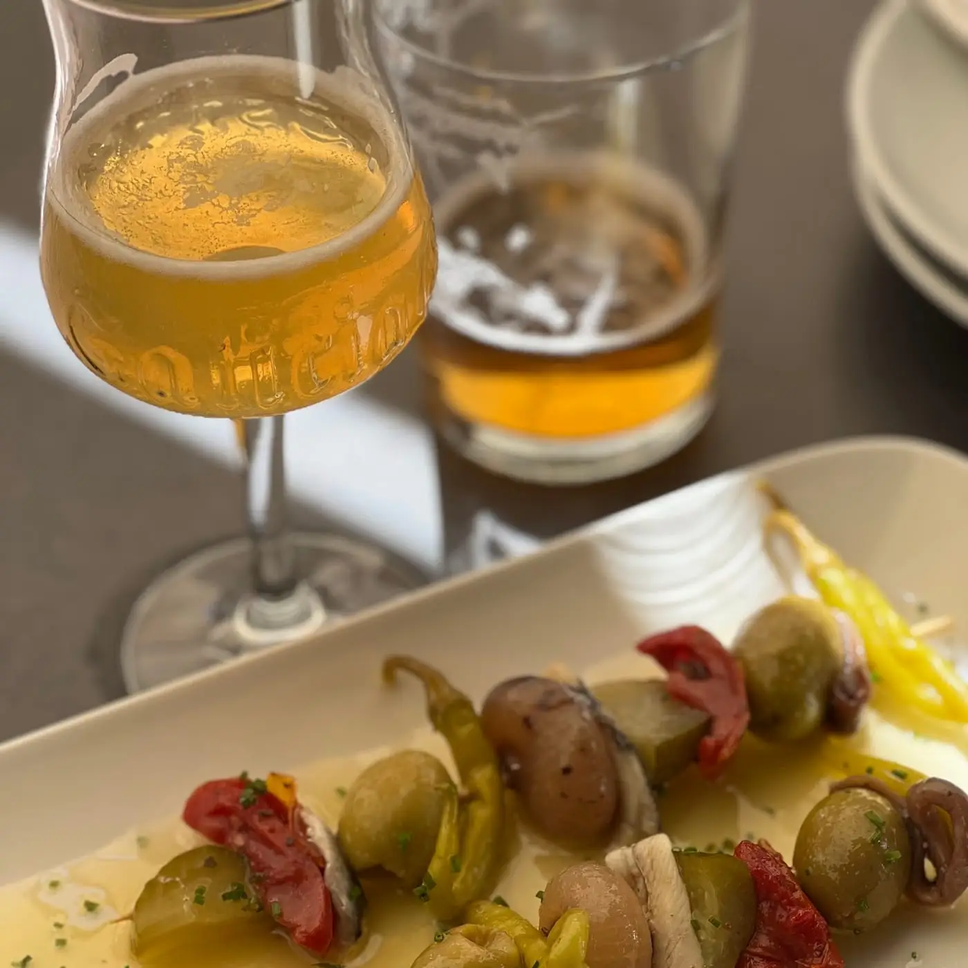 Pinchos con encurtidos, pimientos y tomate acompañados de una copa de sidra